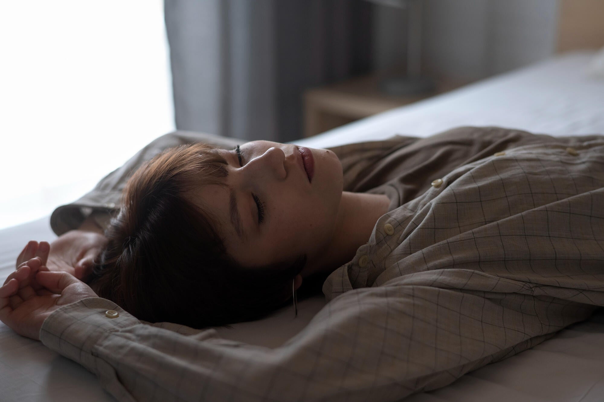 Young woman feeling tired and yawning during the day, showing signs of fatigue.